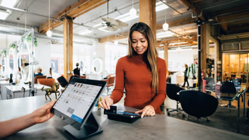 Cliente réglant son achat au comptoir d’une boutique équipée d’une caisse sur tablette