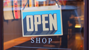 Panneau « Open — Shop » accroché derrière la vitrine d’un commerce de proximité