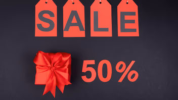 Étiquettes de prix rouges formant le mot « Sale » au-dessus d’un cadeau et de la mention 50 %