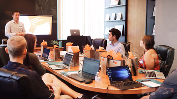 Présentation devant une équipe en salle de réunion, les participants installés avec leurs ordinateurs portables