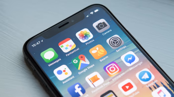 Écran d’accueil d’un smartphone couvert d’icônes d’applications, posé sur une table claire